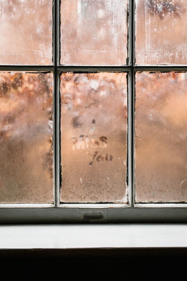 The words "I miss you" written in condensation on a window