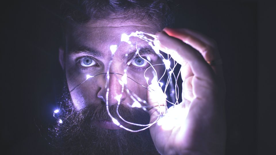 Man holding fairy lights over his eyes. 